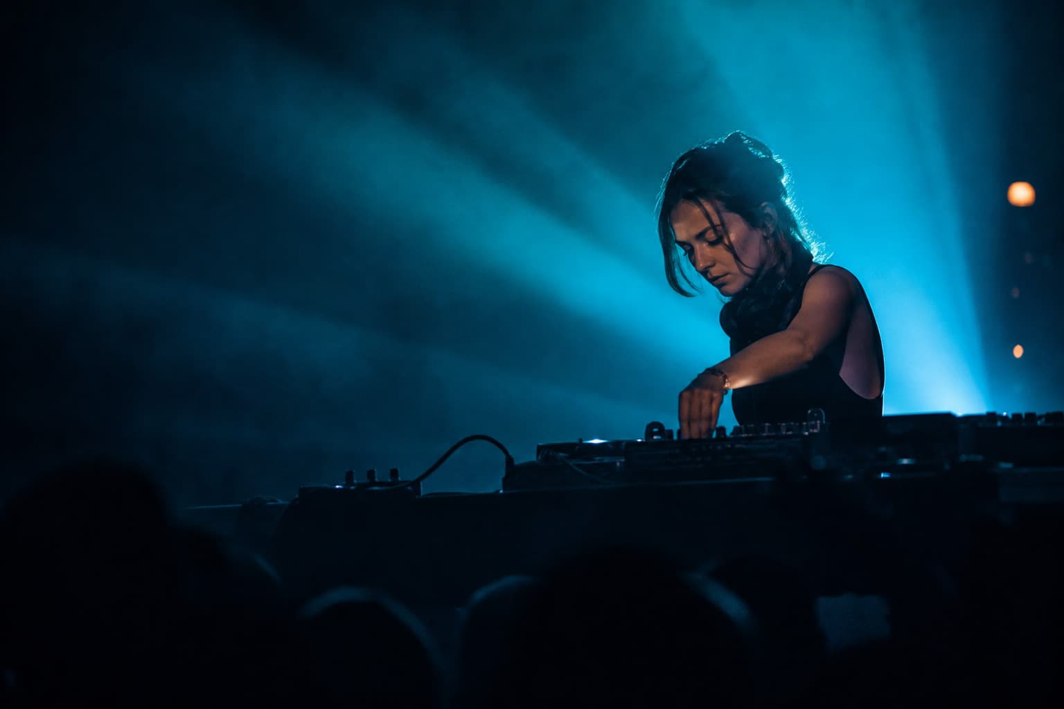 Nova Haller performing behind the booth under blue stage haze